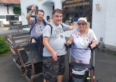 Gruppenfoto der Bewohner in Oberammergau. Einer der Bewohner sitzt in einem alten Pferdeschlitten.